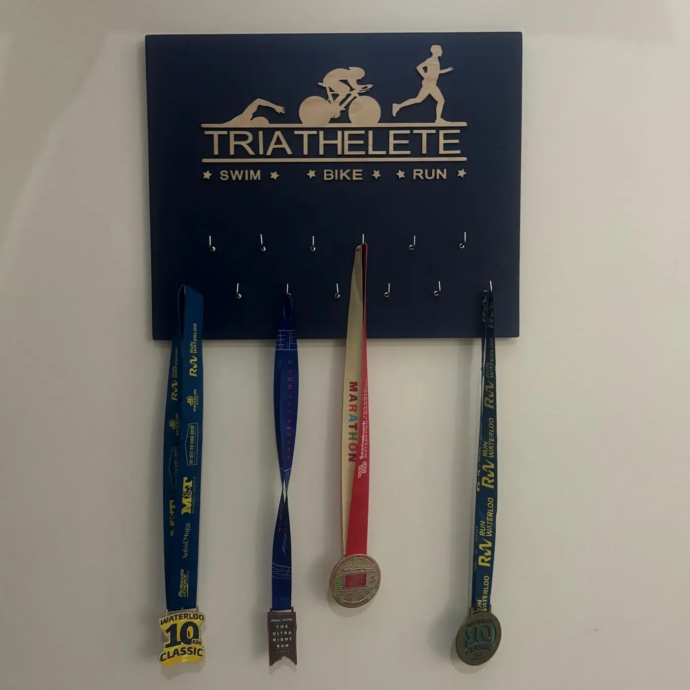 Wooden medal holder with a bib slot and a finisher medal, made by Krishacraft in Waterloo